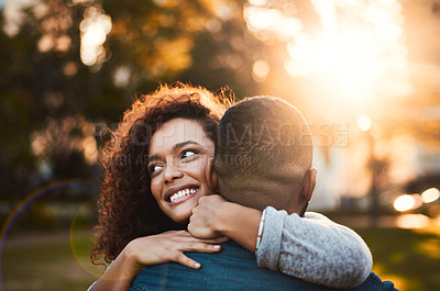 Buy stock photo Shot of a young woman hugging her boyfriend outdoors