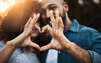 Buy stock photo Shot of a a young couple making a heart shape with their fingers outdoors