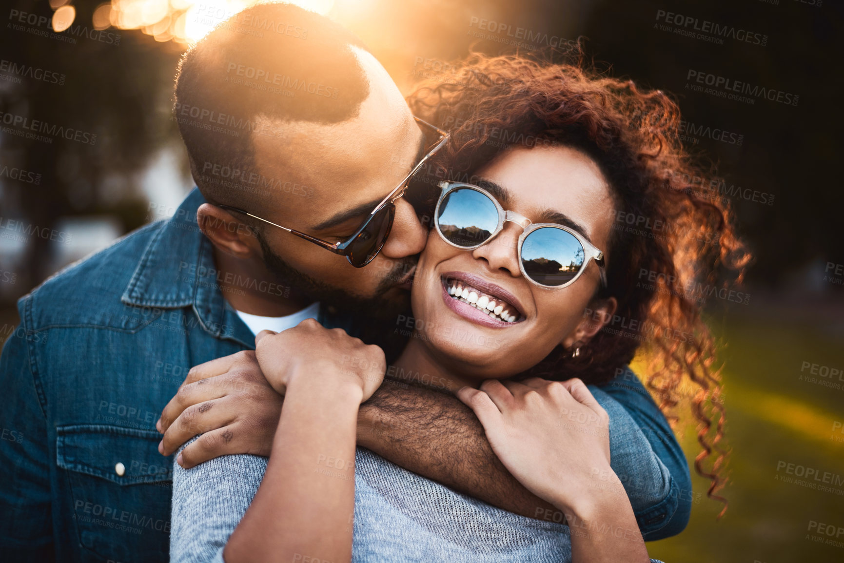 Buy stock photo Kiss, hug and couple in park, sunglasses and romance with relationship, adventure and bonding together. Outdoor, embrace or happy man with woman, peaceful and vacation with trust, excited or kindness