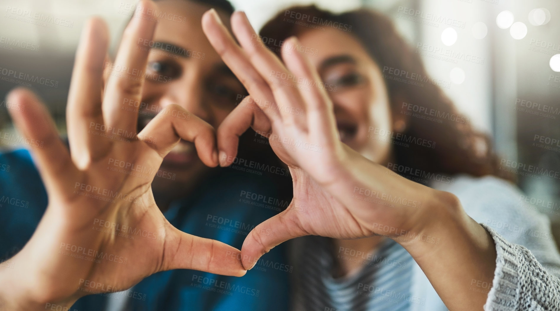 Buy stock photo Shot of a young couple making a heart gesture with their hands outdoors