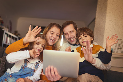 Buy stock photo Cropped shot of an affectionate young family of four video chatting using a digital tablet on the sofa at home