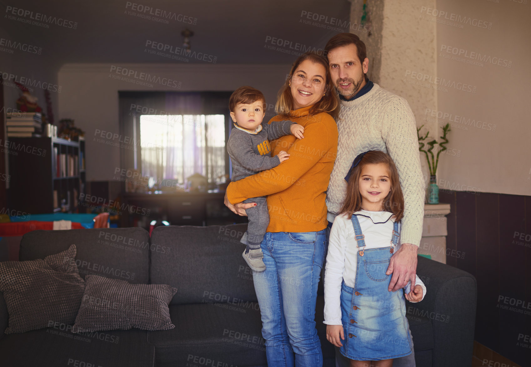 Buy stock photo Cropped portrait of an affectionate young family of four standing in their living room at home
