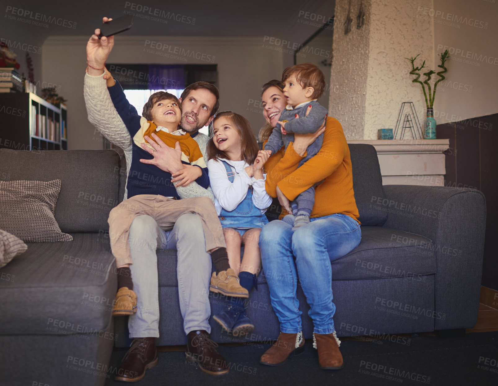 Buy stock photo Full length shot of an affectionate young family of five taking selfies on the sofa at home