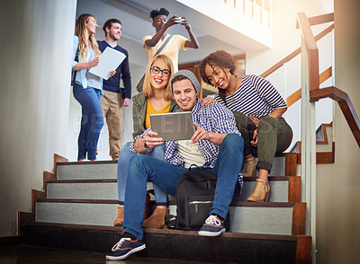Buy stock photo Shot of a group of university students using a digital tablet on the staircase at campus