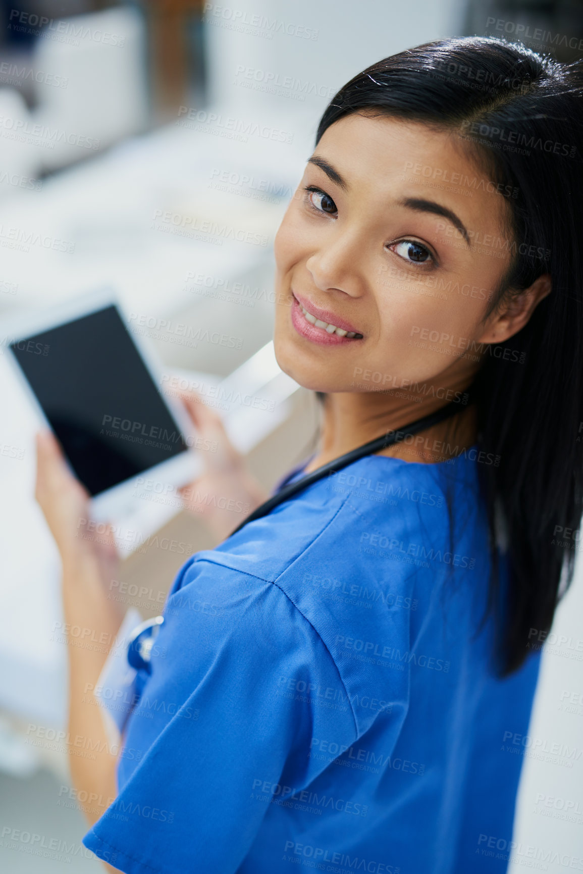 Buy stock photo High angle portrait of an attractive young female nurse using a tablet while standing in the hospital