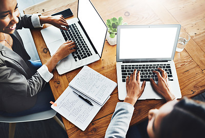 Buy stock photo High angle shot of two businesswomen working on laptops in an office