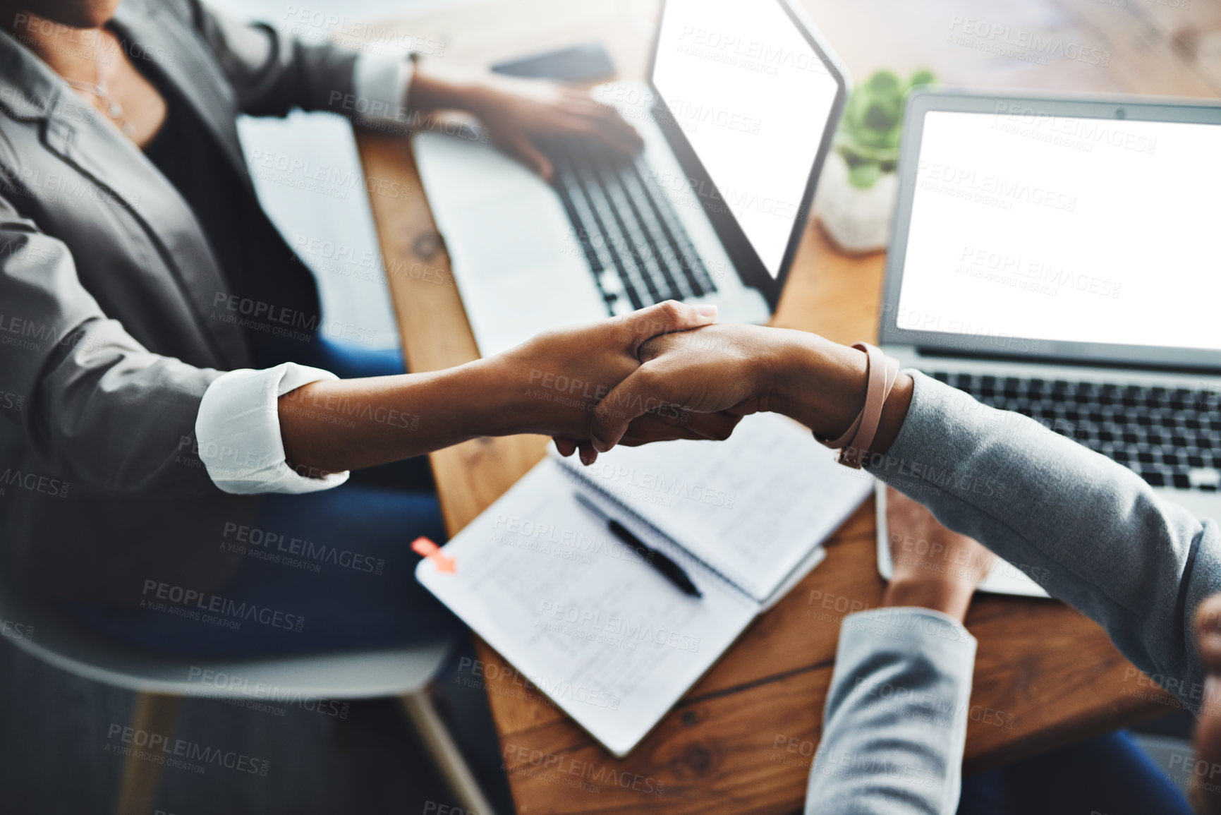 Buy stock photo High angle shot of two businesswomen shaking hands in an office