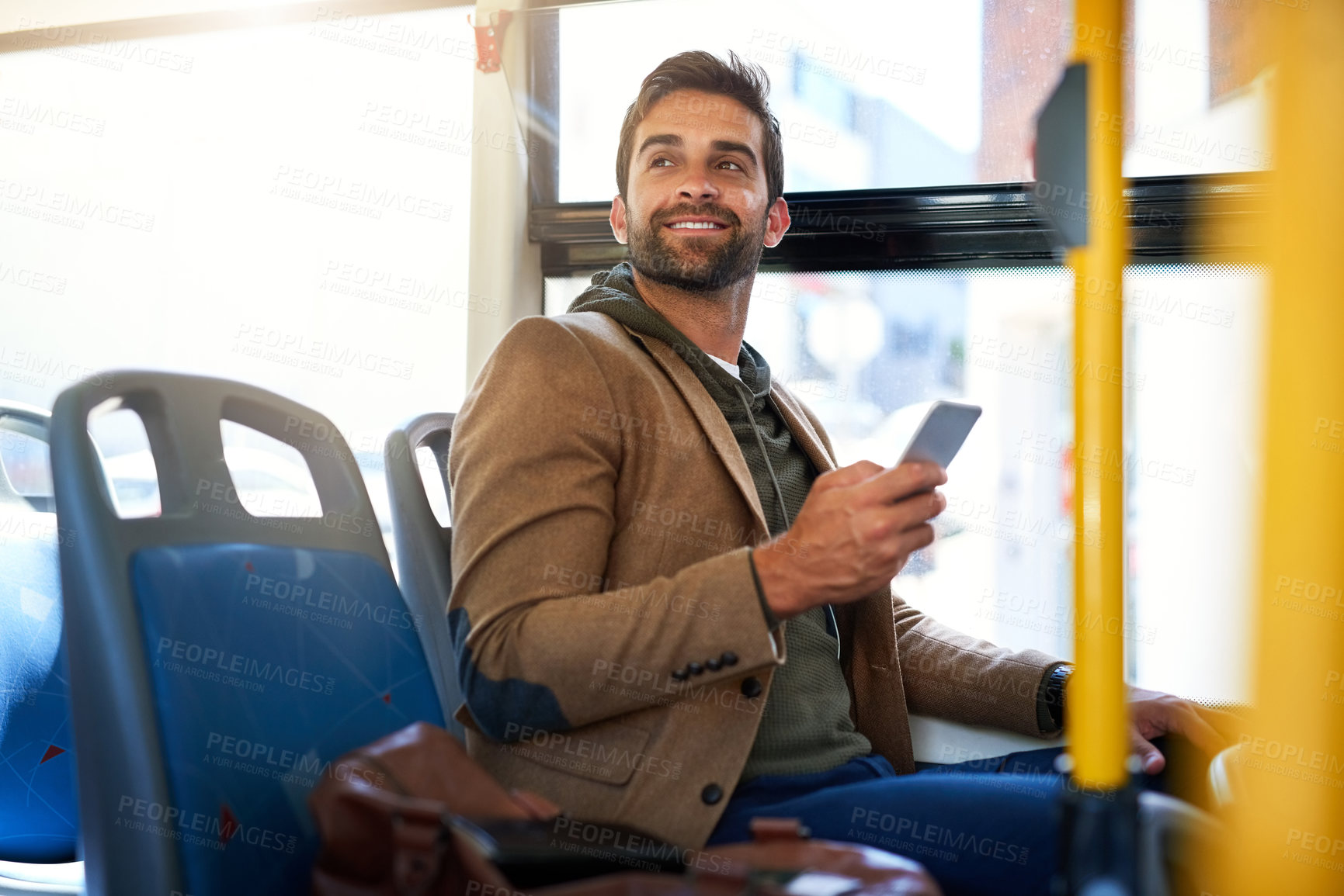 Buy stock photo Cropped shot of a handsome young man sending a text message during his morning bus commute