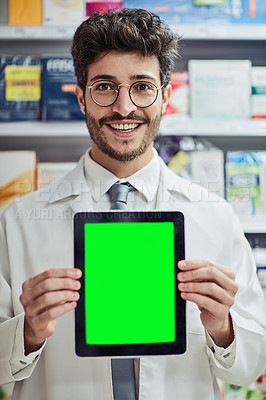 Buy stock photo Cropped portrait of a handsome young male pharmacist holding up a tablet while working in a pharmacy