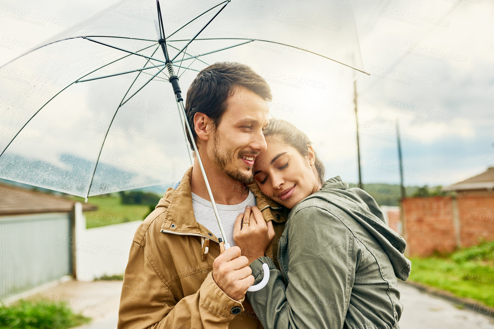 Buy stock photo Cropped shot of a loving couple standing outside with an umbrella