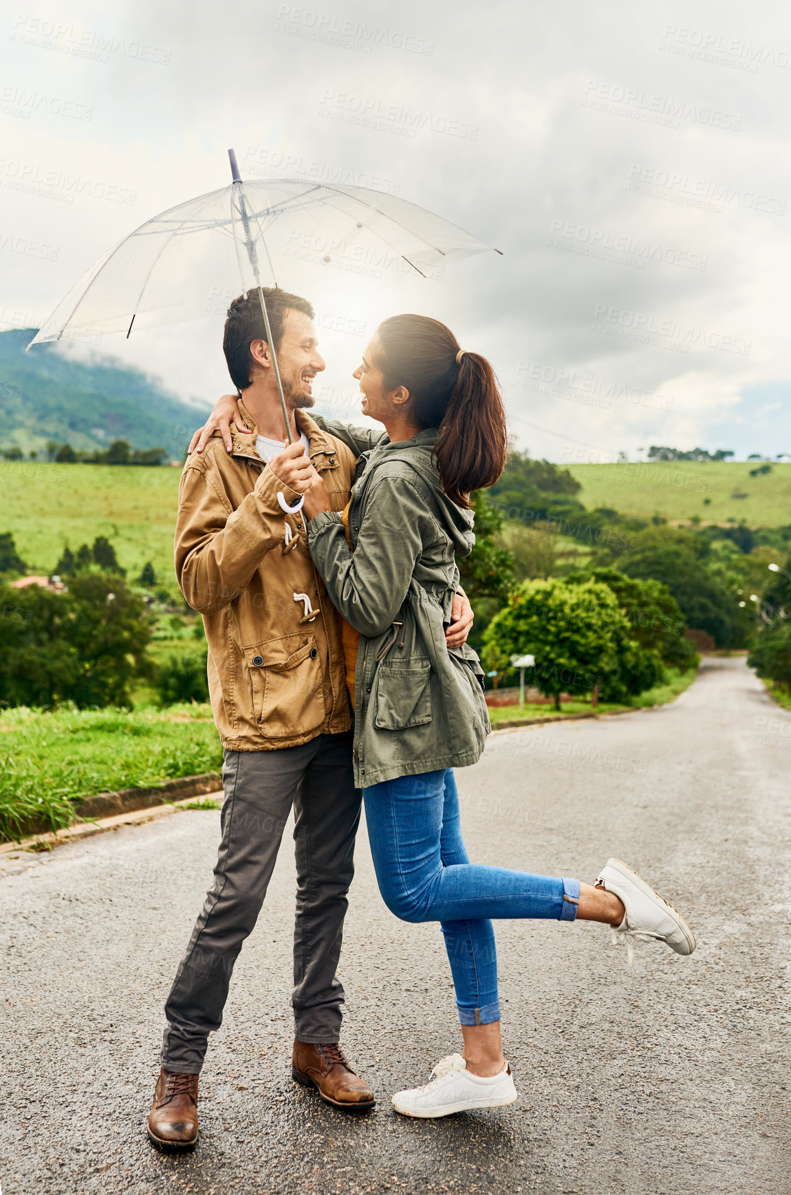 Buy stock photo Laugh, umbrella or happy couple hug outdoor for support, love or bonding together on road. Smile, man and woman with parasol for romantic date, embrace or protection or safety from rain on vacation