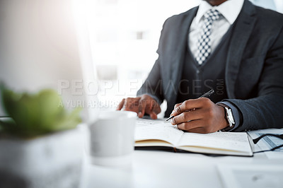Buy stock photo Cropped shot of a businessman using a computer and writing notes at his desk in a modern office