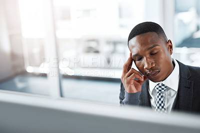 Buy stock photo Shot of a young businessman experiencing stress while working at his desk in a modern office