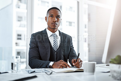 Buy stock photo Shot of a young businessman writing notes and looking thoughtful at his desk in a modern office