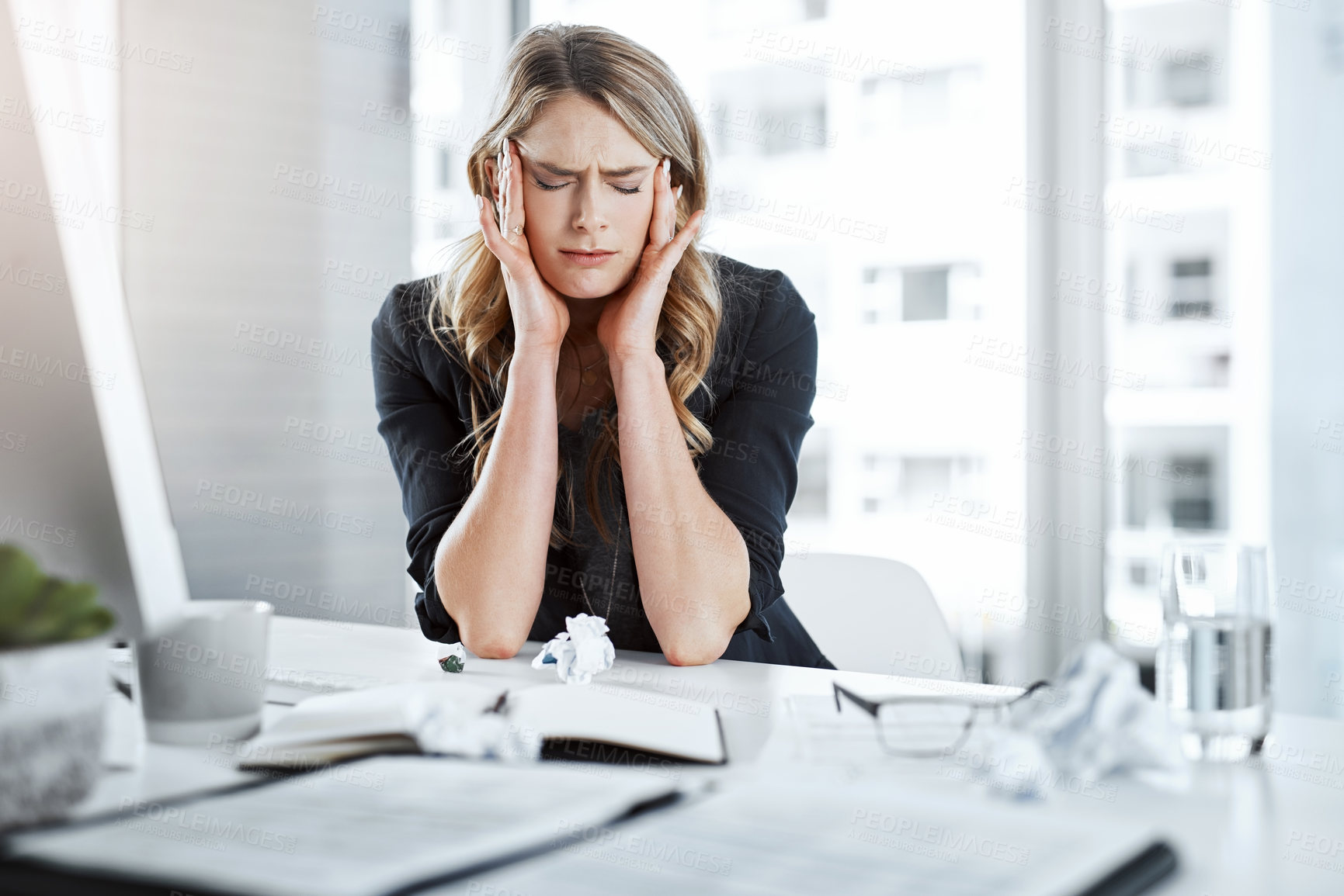 Buy stock photo Shot of a young businesswoman experiencing stress while working at her desk in a modern office