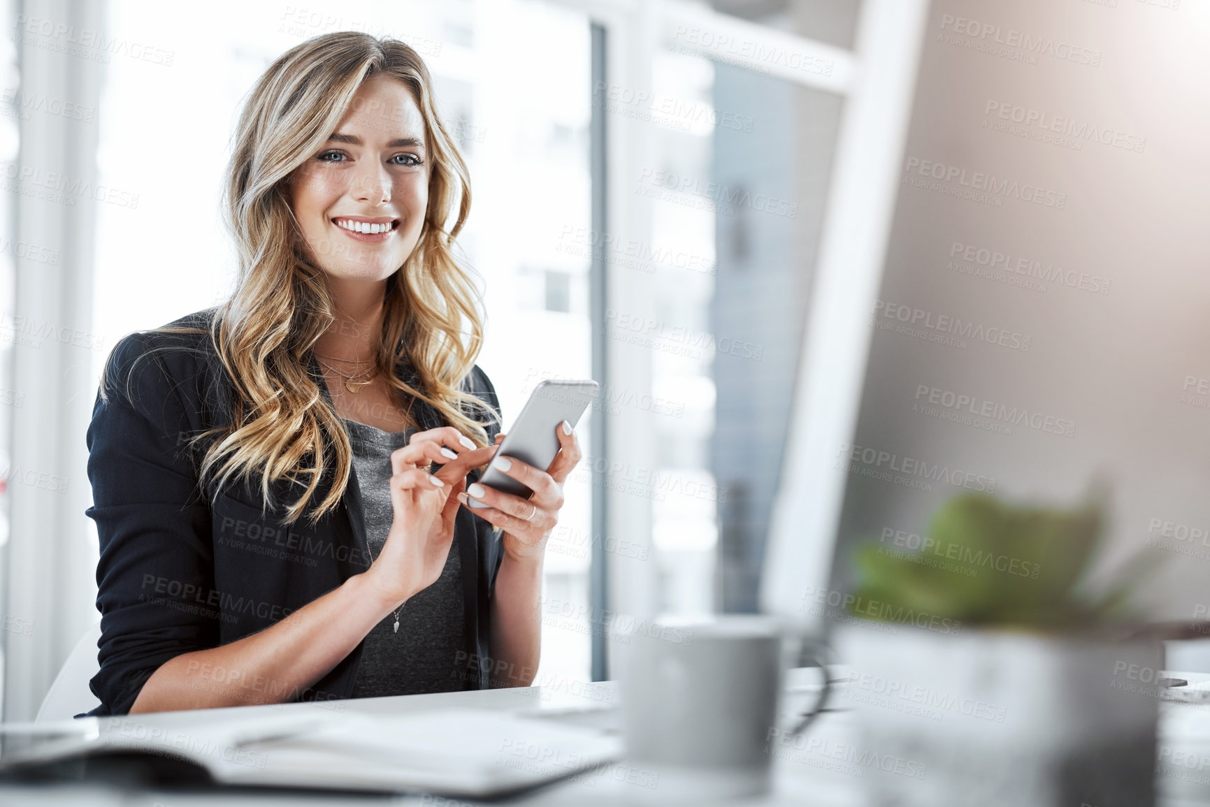 Buy stock photo Portrait of a young businesswoman using a mobile phone at her desk in a modern office