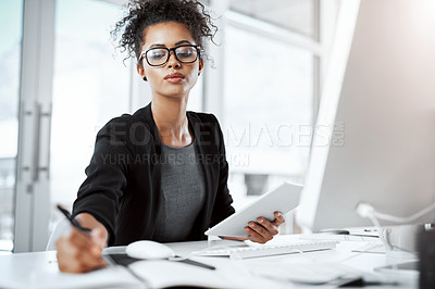 Buy stock photo Shot of a young businesswoman using a digital tablet, computer and writing notes at her desk in a modern office