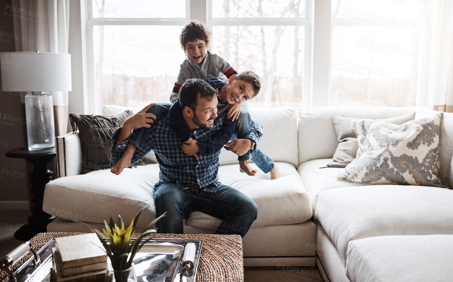 Buy stock photo Goofy, funny and bonding father with children on the sofa for playing, quality time and crazy fun. Love, happy and boy kids piling onto dad with energy on the couch of their family home together
