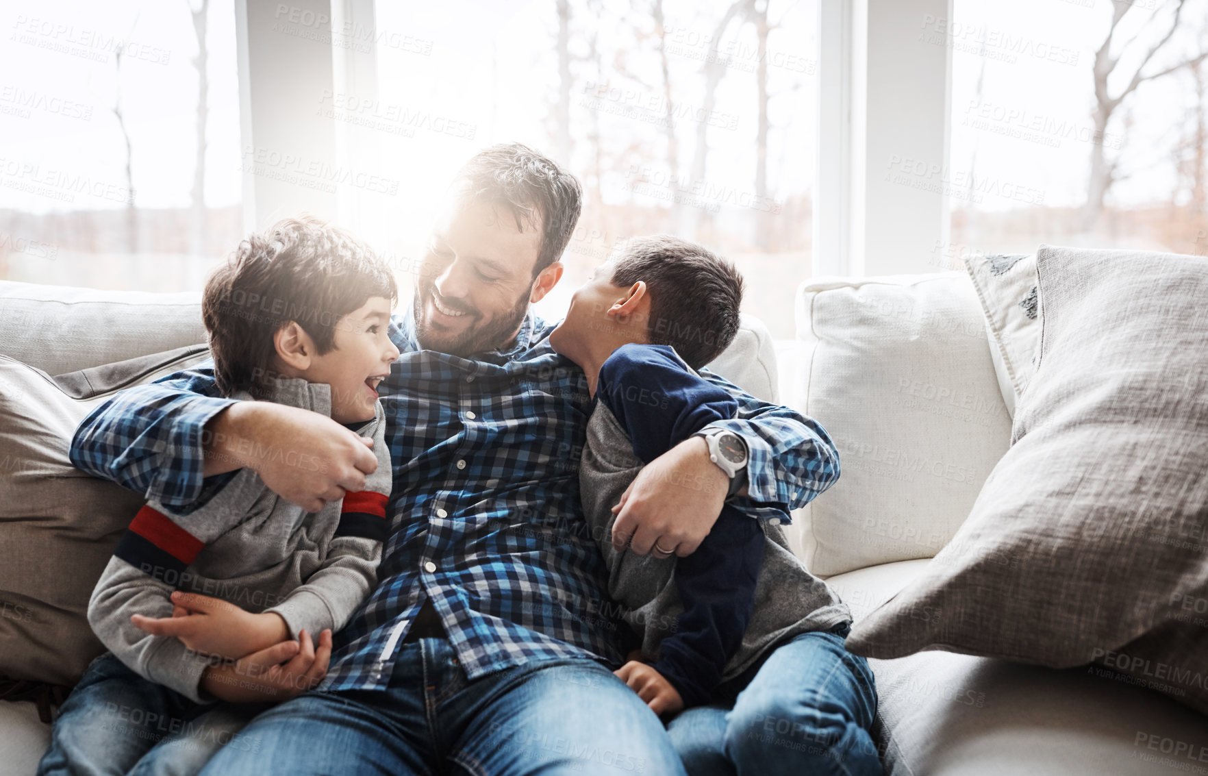 Buy stock photo Morning, happy and father with children on sofa for bonding, loving relationship and relax together in home. Family, lens flare and dad with kids embrace for love, hug and smile in living room