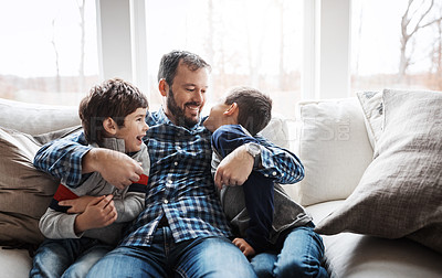 Buy stock photo Hug, playful and father with children on the sofa for love, care and relax in their family home. Happy, funny and dad with boy kids for quality time, affection and comedy on the couch of a house