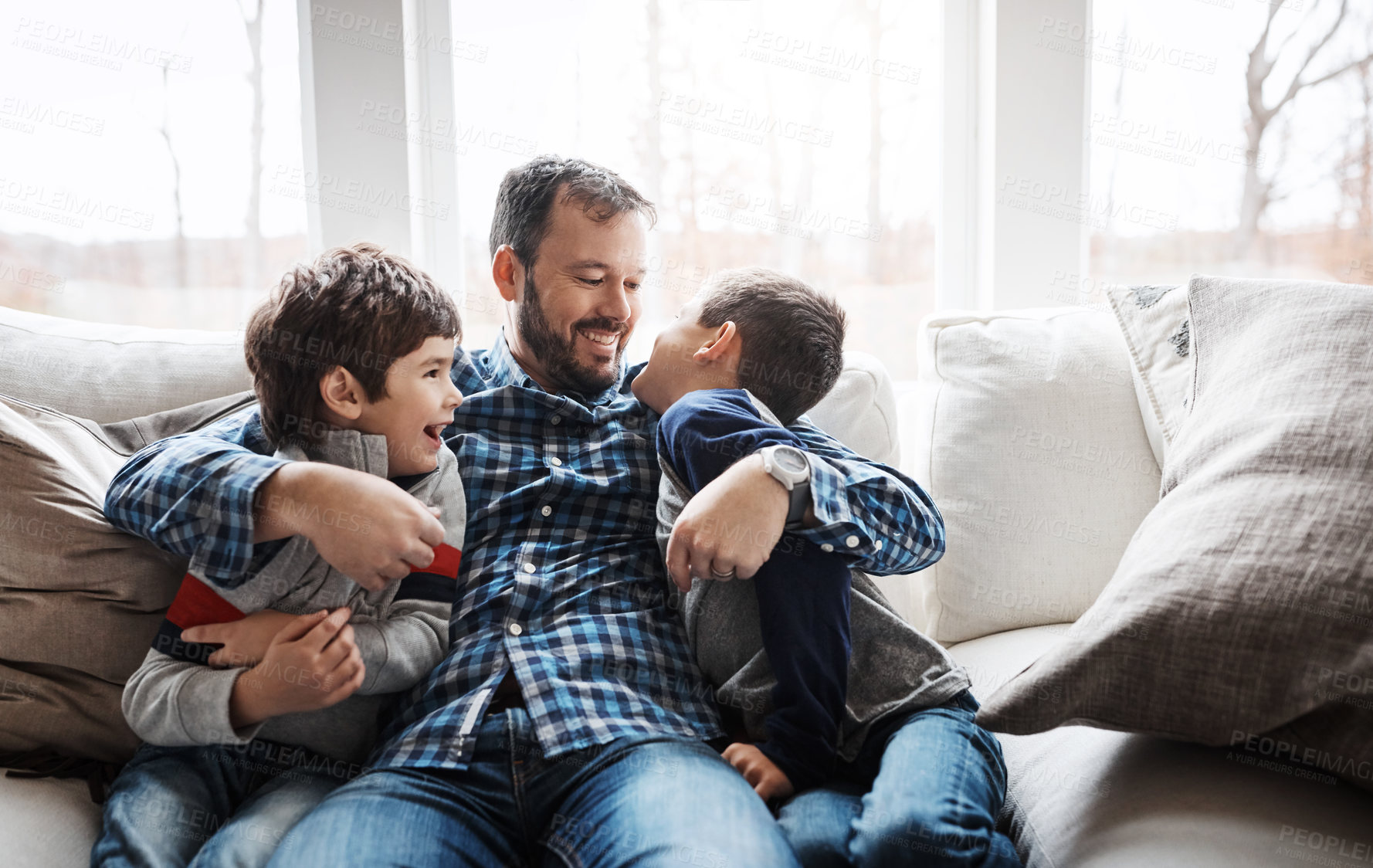 Buy stock photo Hug, playful and father with children on the sofa for love, care and relax in their family home. Happy, funny and dad with boy kids for quality time, affection and comedy on the couch of a house