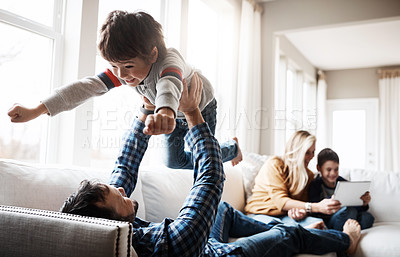 Buy stock photo Family, father and lifting child on sofa for bonding, wellness and play in happy home. Dad playing flying plane in air game with son on living room couch for care, love and bond together