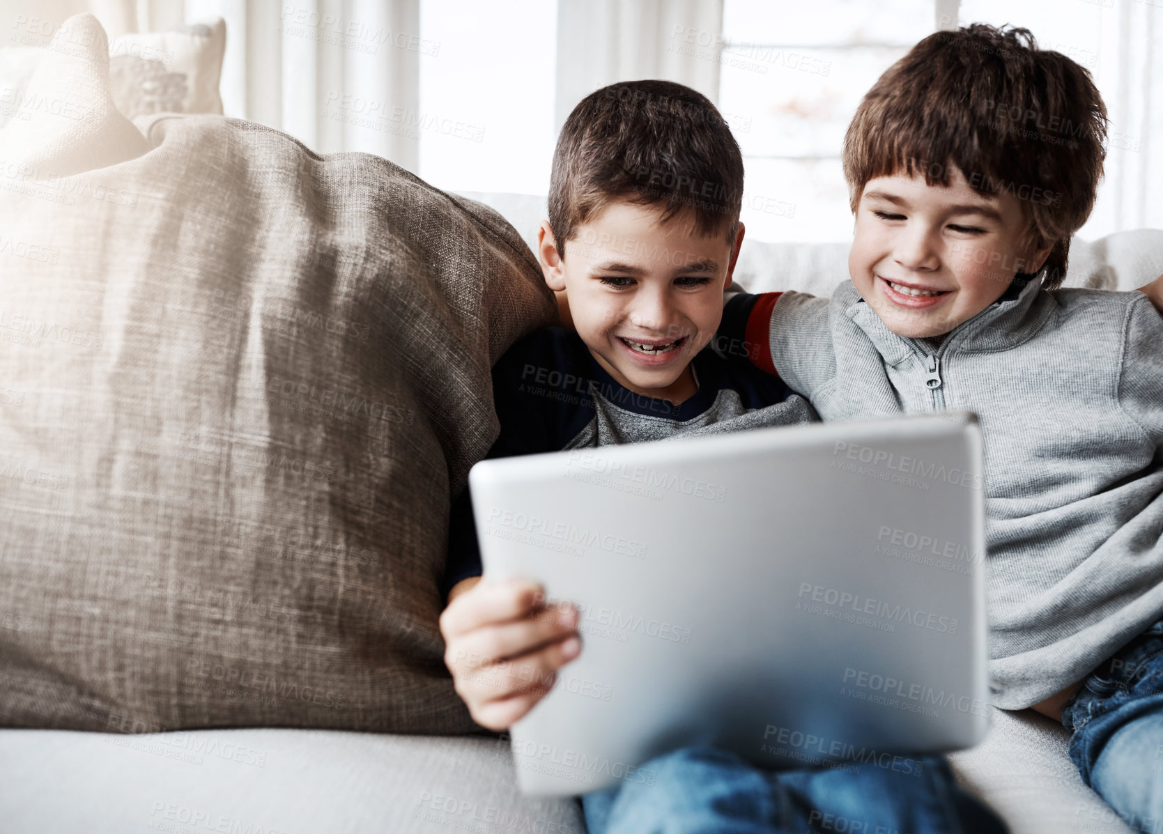 Buy stock photo Shot of two adorable brothers using a digital tablet together while relaxing on the sofa at home
