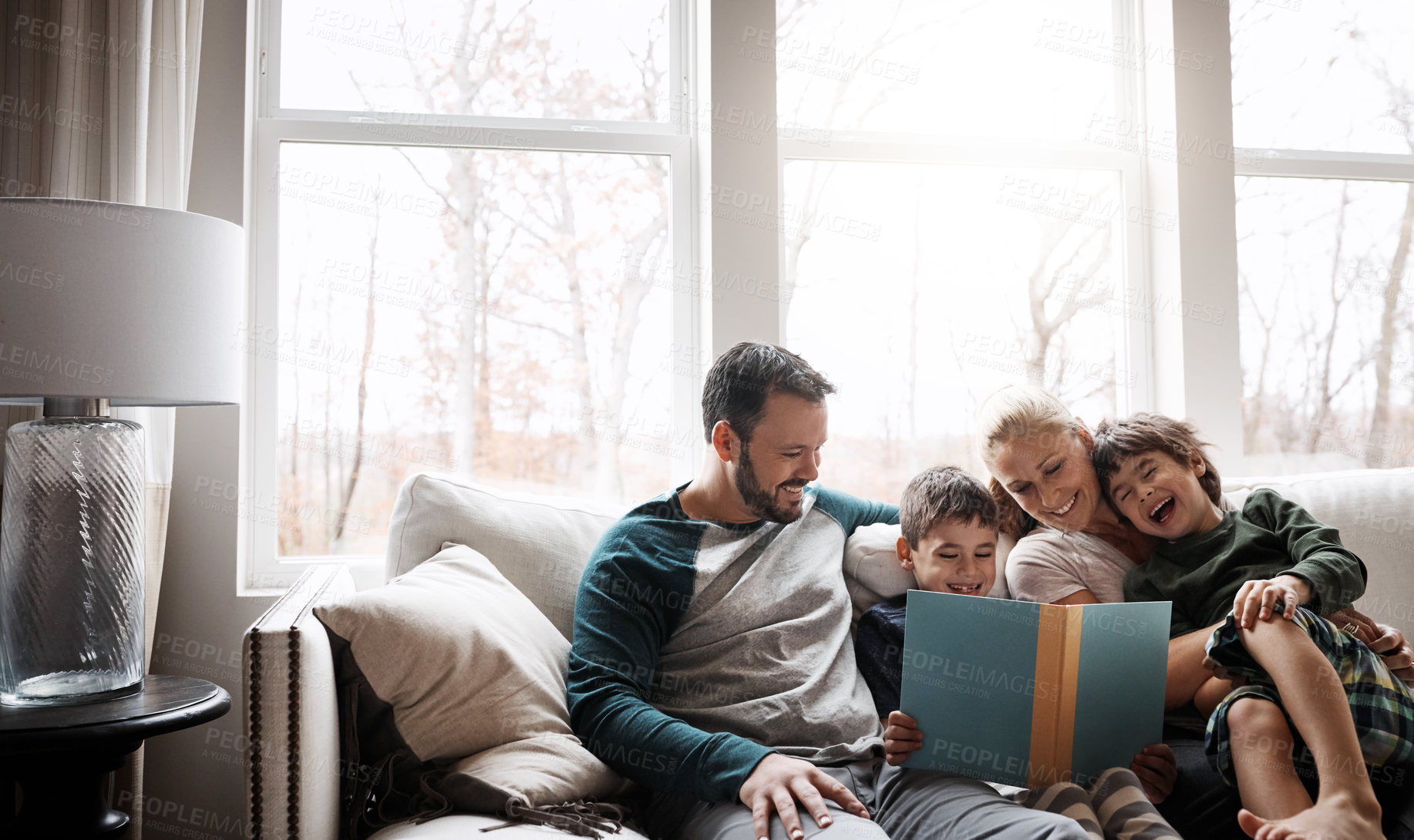 Buy stock photo Books, reading and couple with children on couch for storytelling time in living room of happy home. Love, learning and growth, woman and man with kids, book and fantasy story smile on sofa together.
