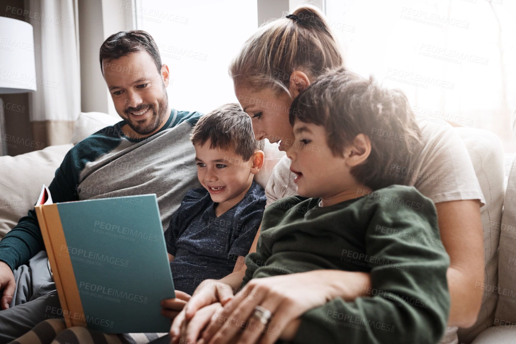 Buy stock photo Relax, children and parents reading a book for bonding, fun and quality time. Knowledge, information and boys excited about learning a story together on the lounge sofa with their mother and father