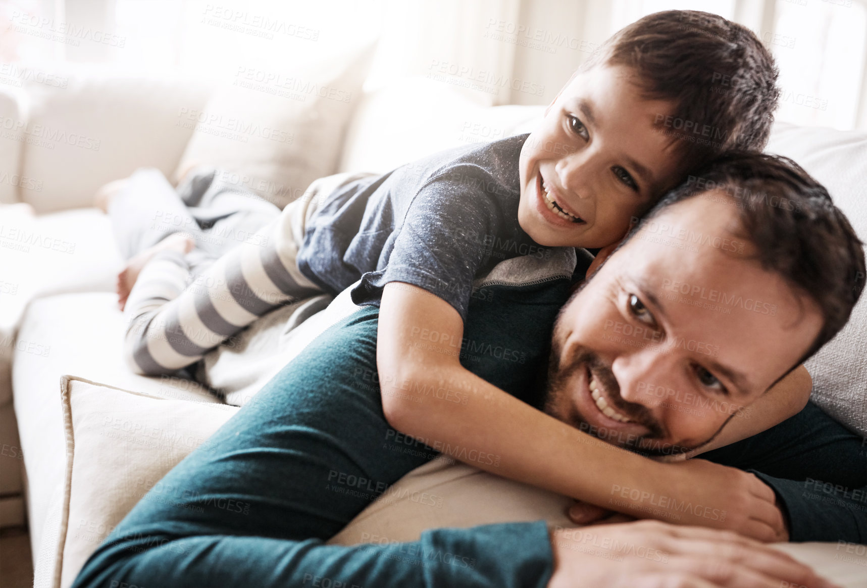 Buy stock photo Hug, fun and child playing with father on the living room sofa to relax in their family home. Happy, funny and dad and boy kid with playful affection while smiling on the couch in the lounge