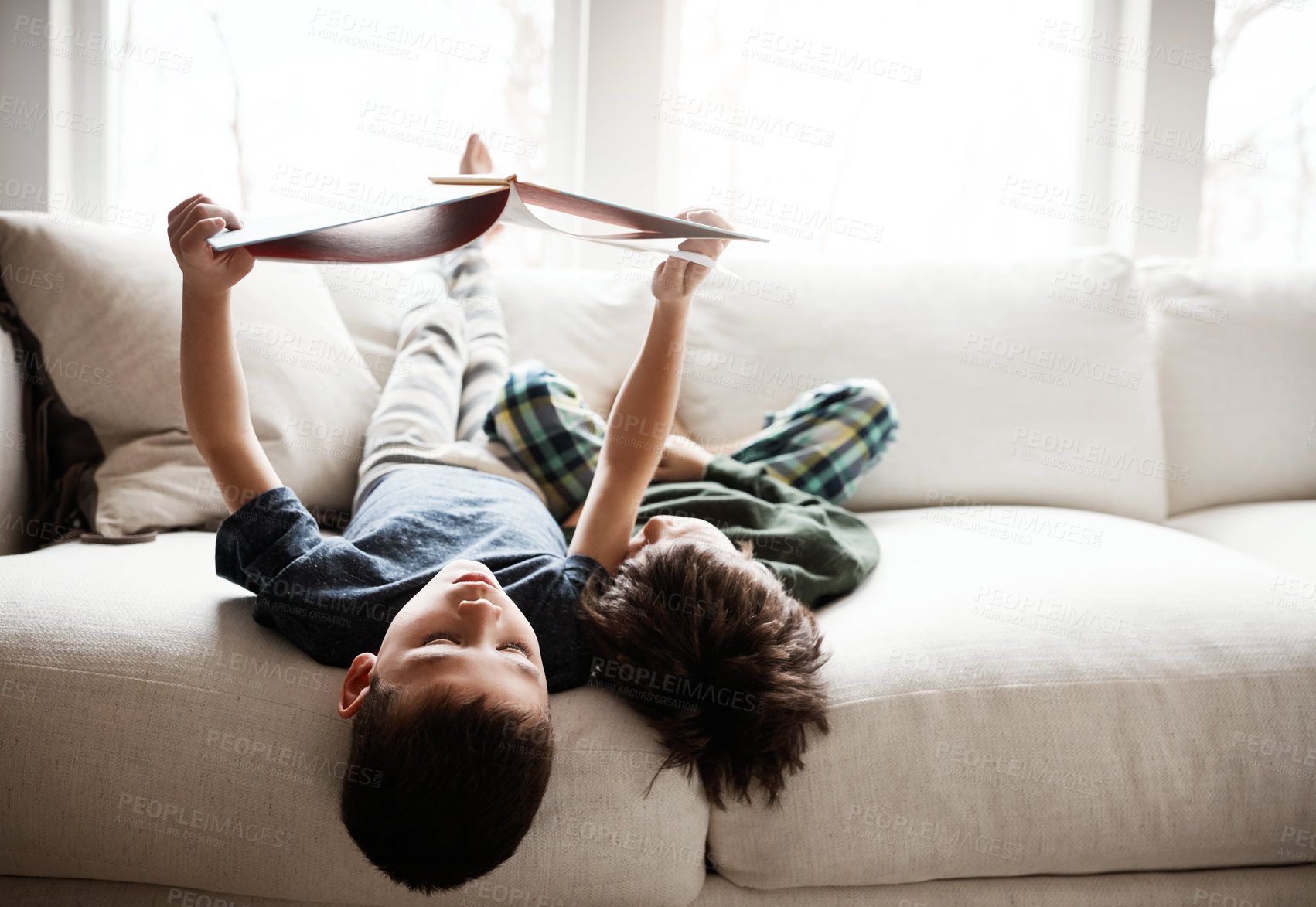 Buy stock photo Upside down, comfortable and children reading books on sofa for knowledge, information and education. Relax, content and boys with a story for happiness, studying and playing on the living room couch