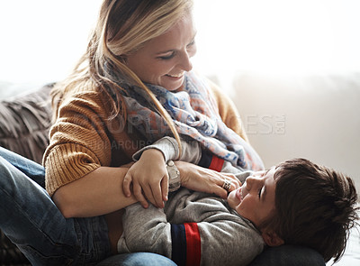 Buy stock photo Mother, child and tickling while together in happy family home with love, care and happiness. Funny woman playing with kid on living room sofa for bonding, energy and quality time at their house