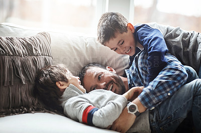 Buy stock photo Father, boy children and laughing together, fun and carefree with love, energy and happy at family home. Man play with kids on sofa, crazy and playful with happiness and excited with laughter
