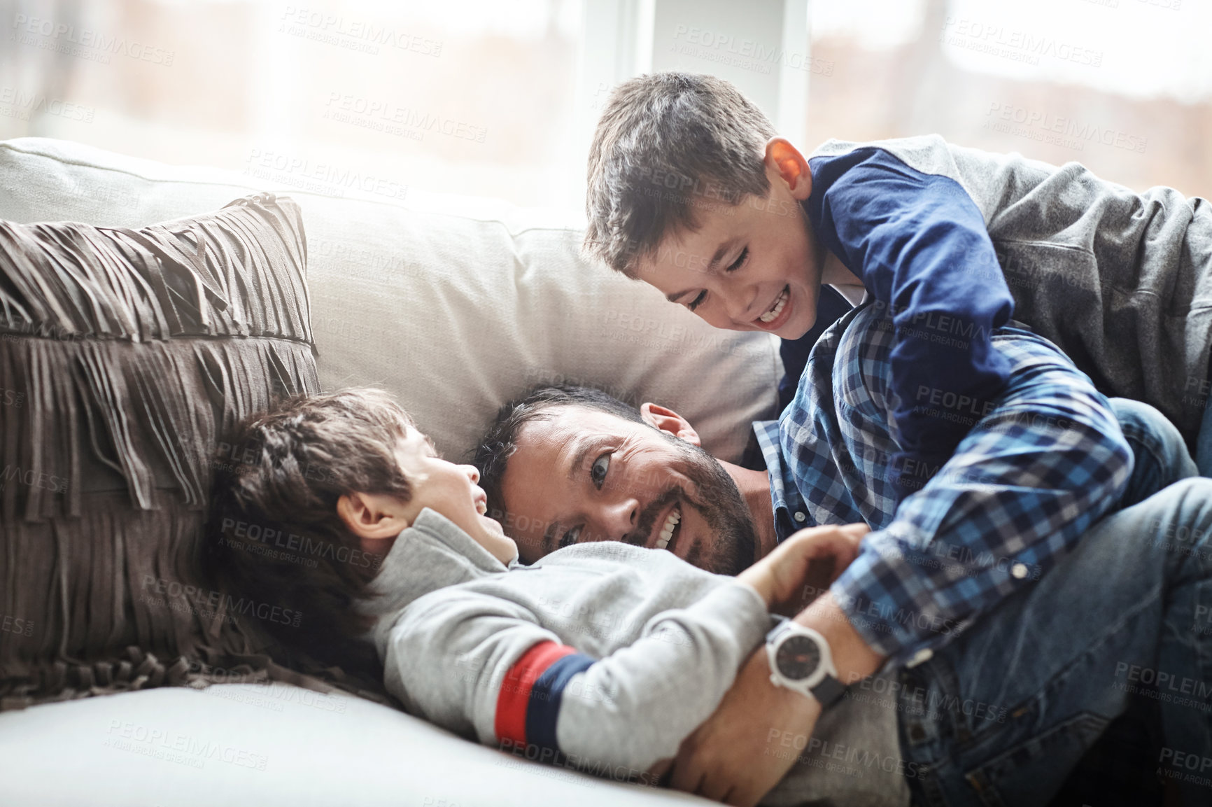Buy stock photo Father, boy children and laughing together, fun and carefree with love, energy and happy at family home. Man play with kids on sofa, crazy and playful with happiness and excited with laughter
