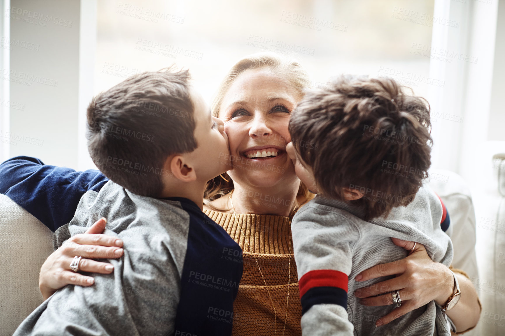 Buy stock photo Kiss, bonding and a mother with children for love, relax and playing in a family home together. Hug, smile and mom with affection for boy kids during quality time on the living room sofa of a house