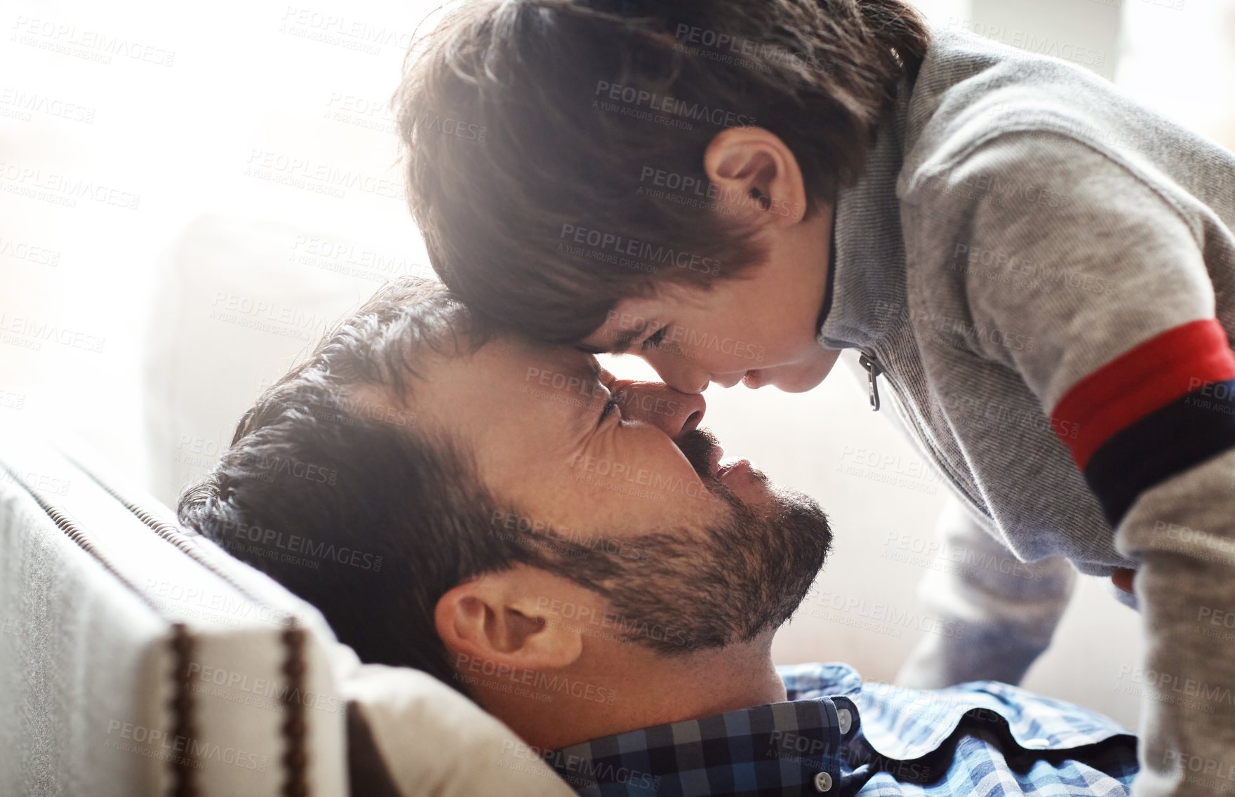 Buy stock photo Father, child and forehead playing on sofa in living room for quality bonding time together at home. Happy dad enjoying holiday, break or play with son relaxing with smile for love and care on couch