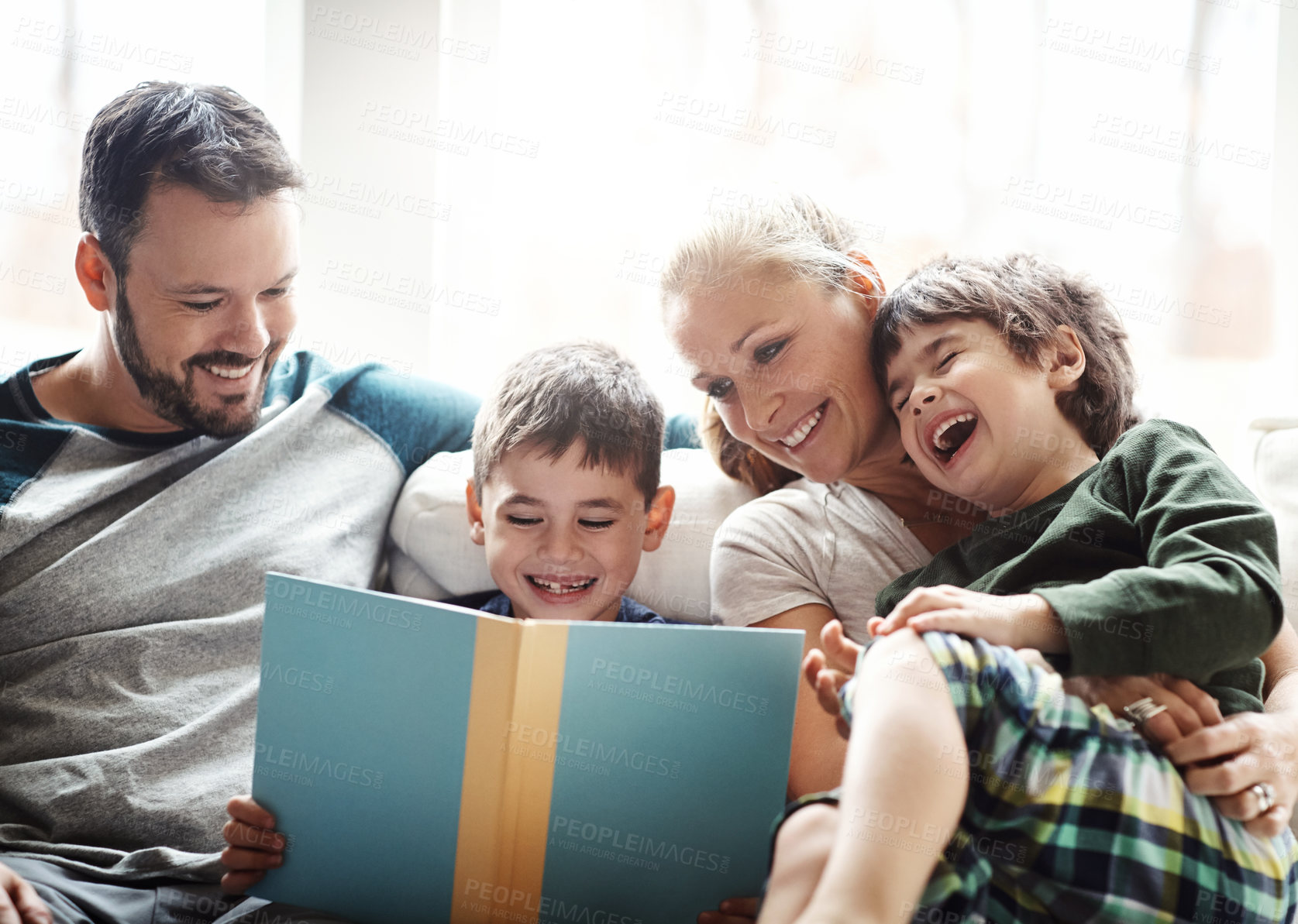 Buy stock photo Family, books and couple reading with kids on sofa, laughing for happy storytelling time at home. Love, learning and child development, man and woman with children reading book on couch with smile.