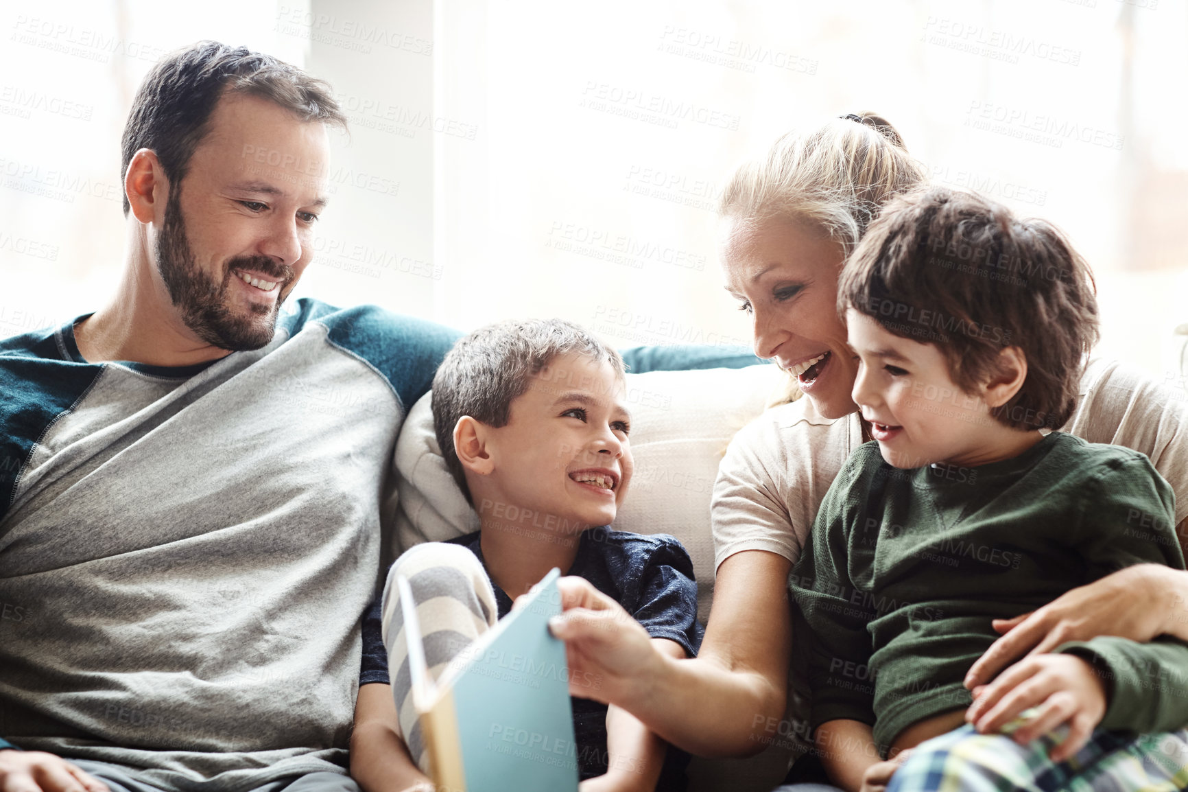 Buy stock photo Mother, father and kids on sofa for storytelling time in living room of happy family home. Love, books and couple with children smile, book and fantasy story time on couch, growth and development.