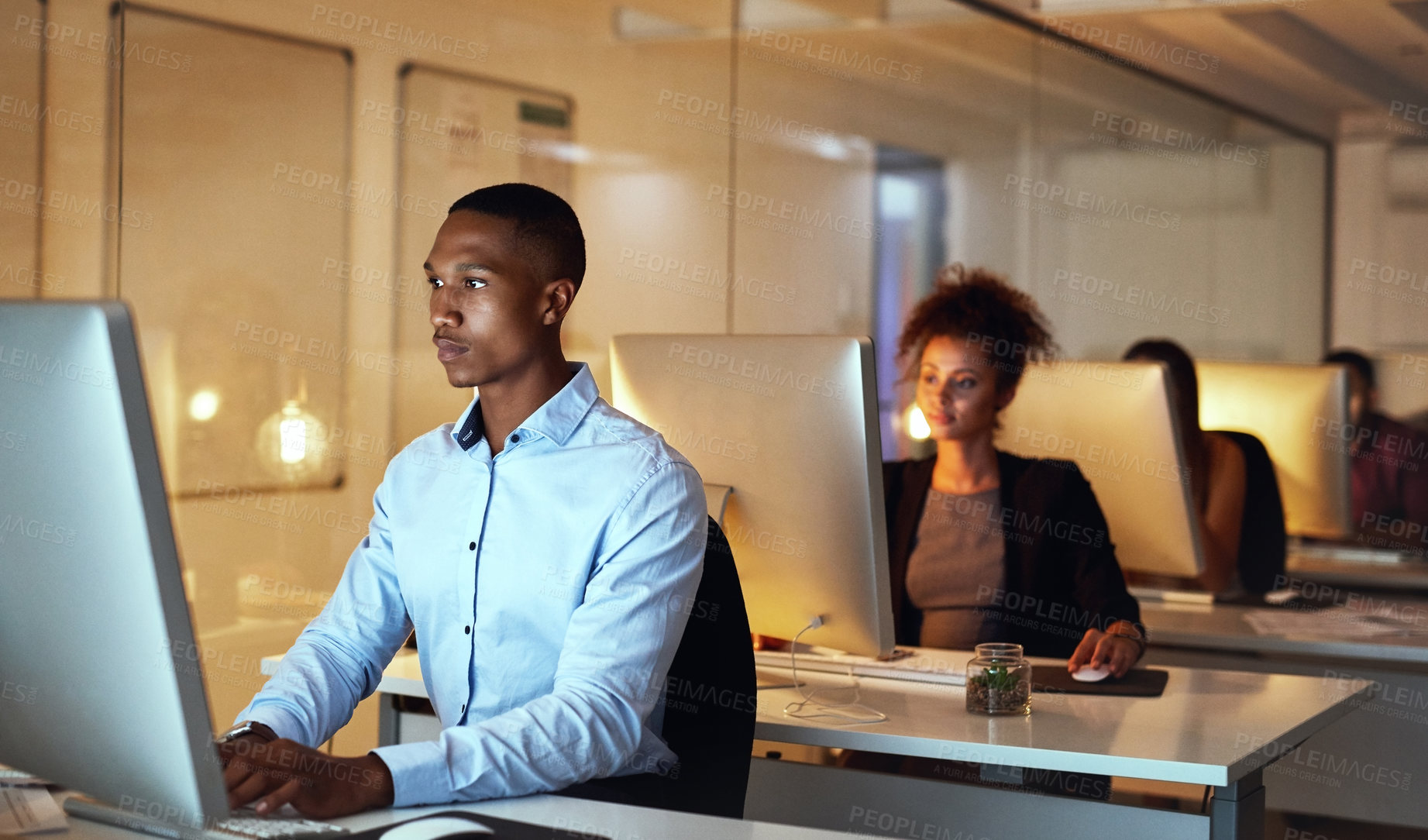 Buy stock photo Shot of a young businessman working late on a computer in an office