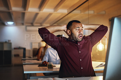 Buy stock photo Shot of a young businessman looking exhausted while working late in an office