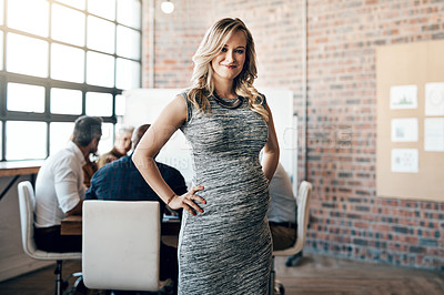 Buy stock photo Modern and professional pregnant businesswoman smiling and standing in a leadership role, in a meeting with work colleagues. Ambitious mother working in management of casual business startup 