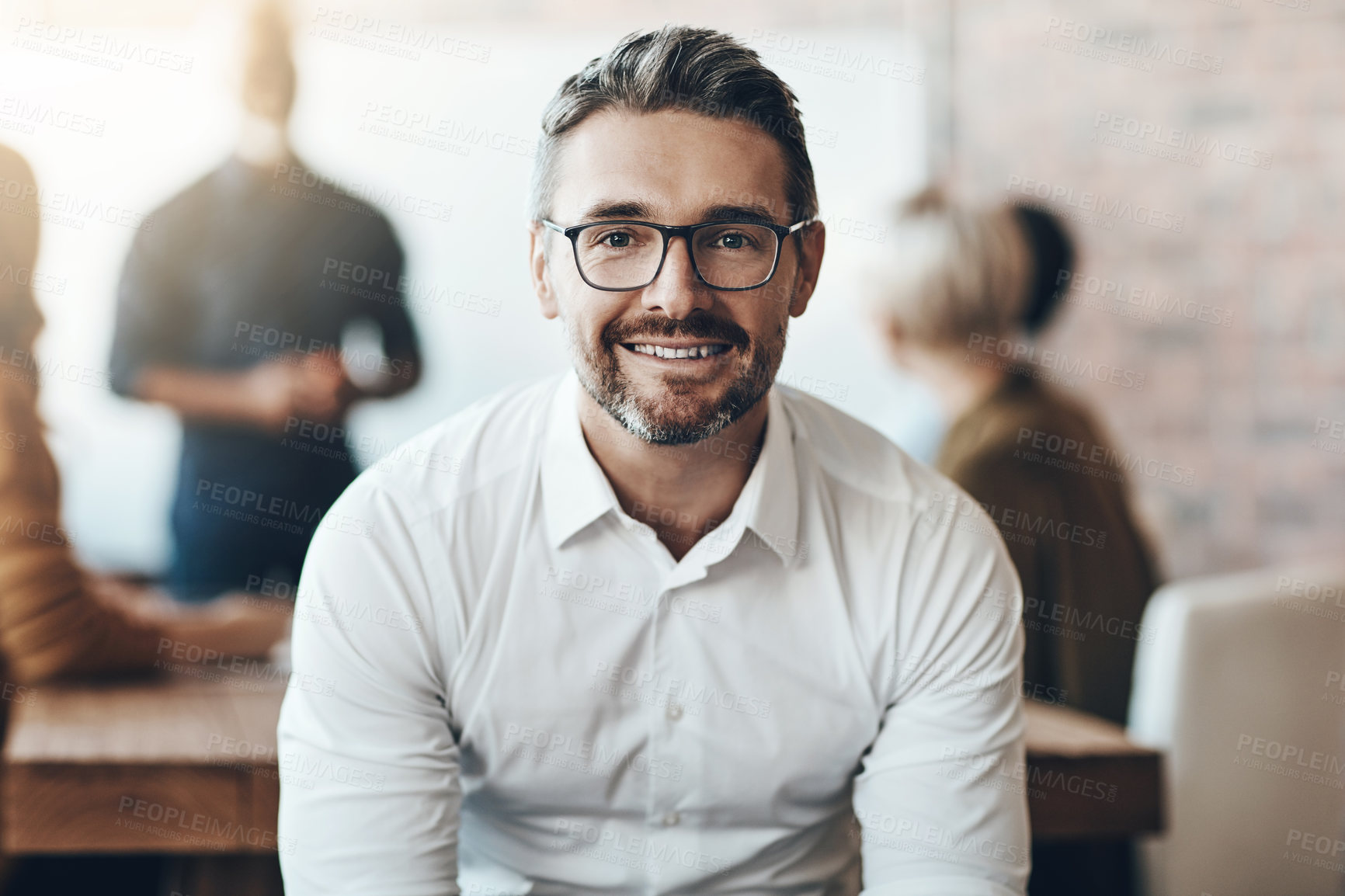 Buy stock photo Leadership, portrait of ceo or businessman smile and sitting in office at work with colleagues behind manager. Entrepreneur or business, leader and smiling male person with glasses sit at workplace 