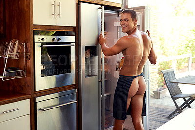 Buy stock photo Cropped shot of a handsome young shirtless man getting items from the refrigerator at home