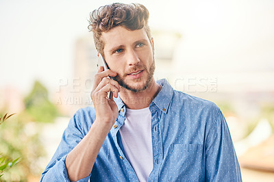 Buy stock photo Shot of a confident young man talking on his cellphone outside during the day