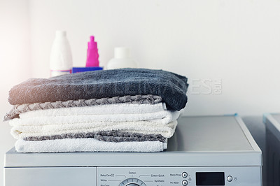 Buy stock photo Shot of a pile of linen folded on top of a washing machine at home