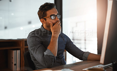 Buy stock photo Shot of a young businessman yawning while working late on a computer in an office