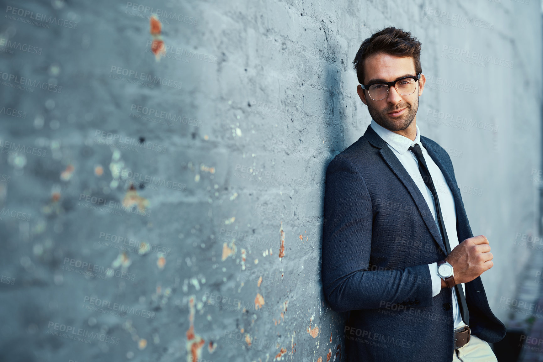 Buy stock photo Cropped portrait of a handsome young businessman standing against a grey facebrick wall