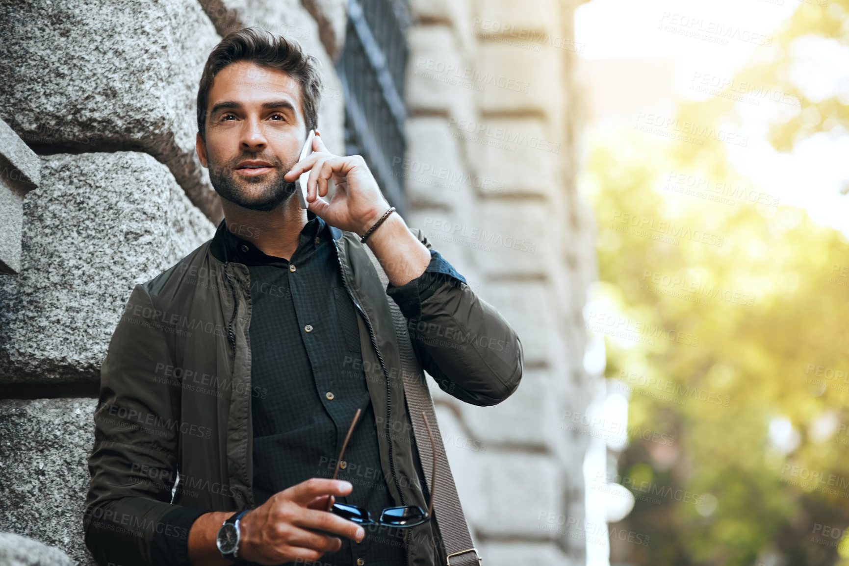 Buy stock photo Cropped shot of a handsome young man making a phonecall while traveling through the city