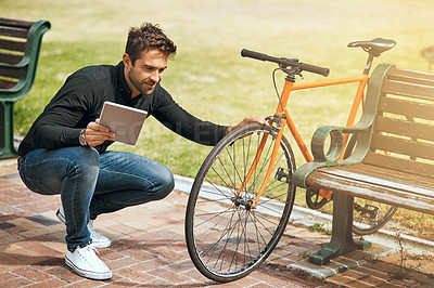Buy stock photo Full length shot of a handsome young man using his tablet while in the park