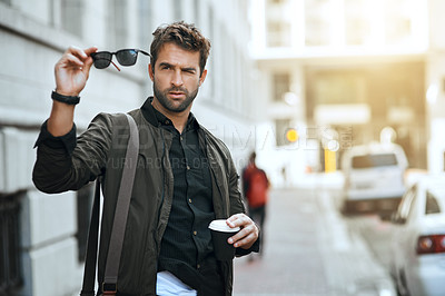 Buy stock photo Cropped shot of a handsome young man checking his sunglasses while traveling through the city